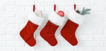 Photo for Christmas socks with gifts hanging on white brick wall - Royalty Free Image