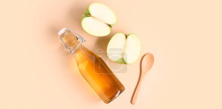 Téléchargez les photos : Bouteille en verre de vinaigre de cidre de pomme sur fond beige - en image libre de droit