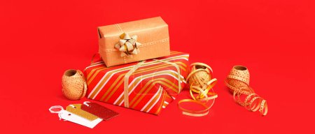 Téléchargez les photos : Cadeaux de Noël et matériaux d'emballage sur fond rouge - en image libre de droit