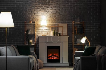 Téléchargez les photos : Intérieur du salon sombre avec cheminée, canapés et lampes incandescentes - en image libre de droit