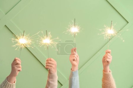 Photo for Women with Christmas sparklers on green background - Royalty Free Image