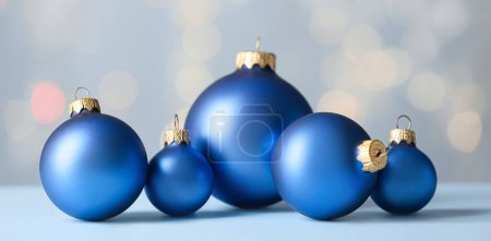 Beautiful blue Christmas balls on table against blurred lights Poster 623680258