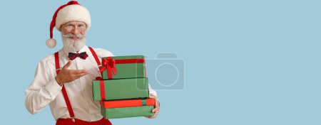 Téléchargez les photos : Père Noël avec des cadeaux sur fond bleu clair avec espace pour le texte - en image libre de droit