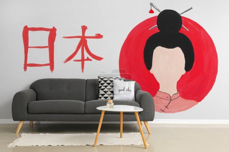 Foto de Elegante mesa y sofá cerca de la pared con imagen de geisha - Imagen libre de derechos