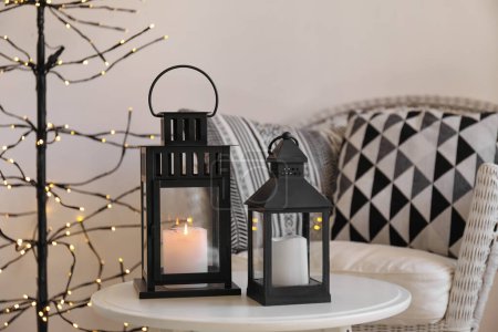 Photo for Black Christmas lanterns with burning candles on table in living room - Royalty Free Image