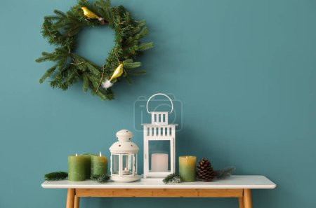 Photo for Christmas lanterns with burning candles, fir branches and cone on table near blue wall - Royalty Free Image