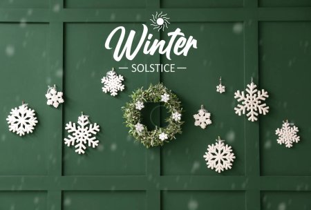 Foto de Hermosos copos de nieve y corona de Navidad en la pared verde. Celebración del solsticio de invierno - Imagen libre de derechos