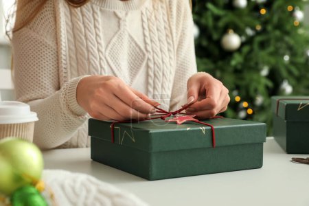 Foto de Mujer atando arco de la caja de regalo de Navidad en la mesa, primer plano - Imagen libre de derechos