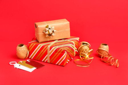 Téléchargez les photos : Composition avec cadeau de Noël et matériaux d'emballage sur fond rouge - en image libre de droit