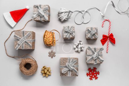 Téléchargez les photos : Composition avec différents cadeaux de Noël, décor et matériaux d'emballage sur fond gris - en image libre de droit