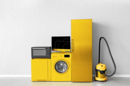 Different yellow household appliances near light wall