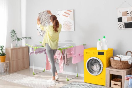 Téléchargez les photos : Jeune femme au foyer faisant la lessive à la maison - en image libre de droit