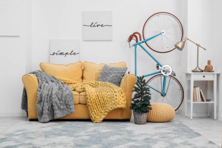 Foto de Interior de la sala de estar con bicicleta, sofá amarillo y pequeño árbol de Navidad - Imagen libre de derechos