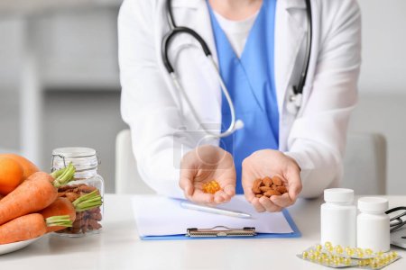 Photo for Female doctor with vitamins and almonds sitting at table in clinic, closeup - Royalty Free Image