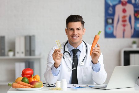 Photo for Male doctor with vitamins and vegetables sitting at table in clinic - Royalty Free Image
