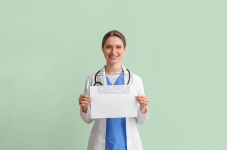 Foto de Médico femenino con hoja de papel en blanco sobre fondo verde - Imagen libre de derechos