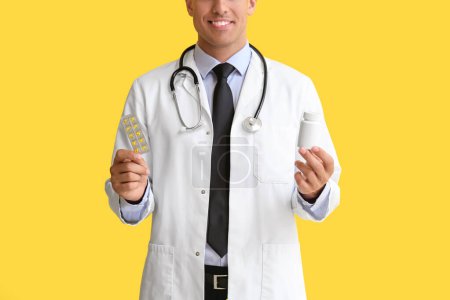 Photo for Male doctor with vitamins on yellow background - Royalty Free Image