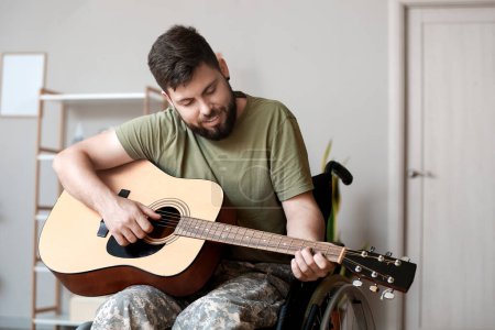 Foto de Joven soldado en silla de ruedas tocando la guitarra en casa - Imagen libre de derechos