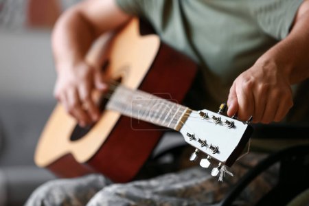 Foto de Joven soldado en silla de ruedas tocando la guitarra en casa, primer plano - Imagen libre de derechos