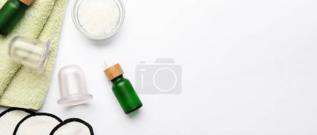 Photo for Vacuum jars for anti-cellulite massage, clean towel. sea salt and bottles of essential oil on white background with space for text - Royalty Free Image