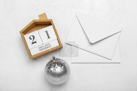Photo for Calendar with text 21 DAYS UNTIL HOLIDAYS, envelopes and Christmas ball on white background - Royalty Free Image