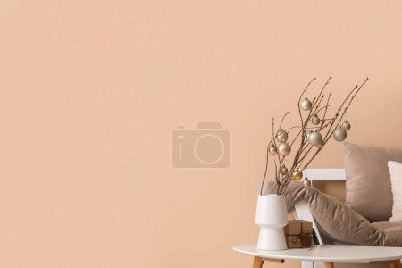 Téléchargez les photos : Vase avec branches d'arbre, boules de Noël et cadeau sur la table dans le salon - en image libre de droit