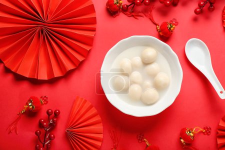Bowl of tasty tangyuan and Chinese decor on red background. Dongzhi Festival