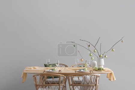 Photo for Vases with tree branches and green Christmas balls on dining table near grey wall - Royalty Free Image