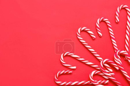 Foto de Composición con sabrosos bastones de caramelo sobre fondo rojo - Imagen libre de derechos