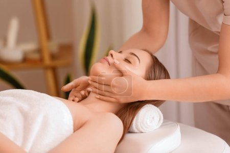 Photo for Pretty young woman receiving face massage in beauty salon - Royalty Free Image