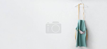 Photo for Clean apron hanging on light wall with space fro text - Royalty Free Image