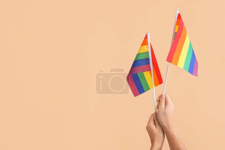 Foto de Manos femeninas con banderas LGBT sobre fondo de color - Imagen libre de derechos