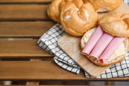 Photo for Delicious kaiser rolls with butter and ham on wooden board - Royalty Free Image