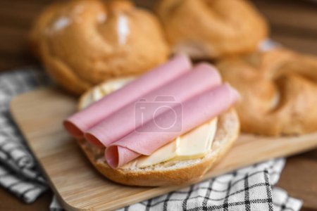 Photo for Delicious kaiser rolls with butter and ham on wooden board - Royalty Free Image