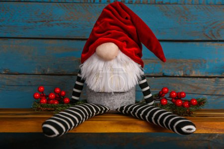 Téléchargez les photos : Gnome de Noël, branches de sapin et baies sur étagère sur fond de bois de couleur - en image libre de droit