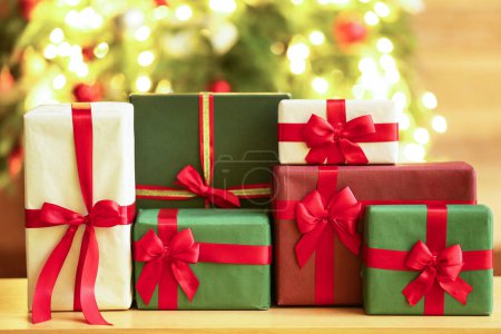 Téléchargez les photos : Cadeaux sur la table contre l'arbre de Noël flou - en image libre de droit