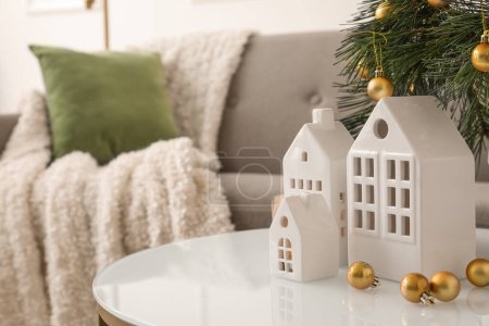 Téléchargez les photos : Bougeoirs en forme de maison avec branches de Noël et boules sur la table dans le salon - en image libre de droit