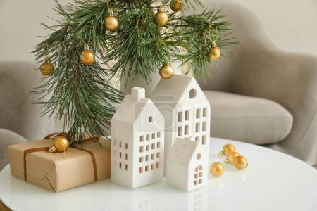 Téléchargez les photos : Vase avec branches de Noël, boules et bougeoirs en forme de maison sur la table dans le salon - en image libre de droit