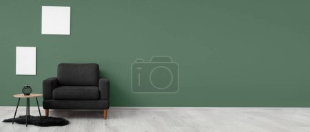 Foto de Cómodo sillón negro y mesa cerca de la pared verde. Banner para el diseño - Imagen libre de derechos