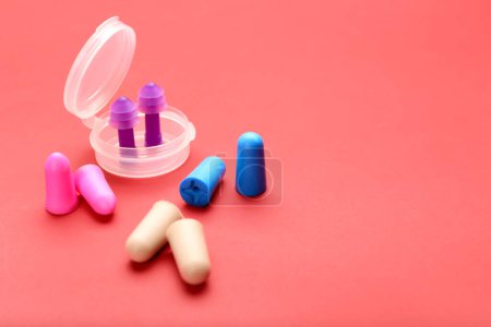 Plastikbehälter und verschiedene Ohrstöpsel auf farbigem Hintergrund