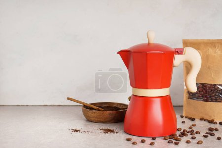 Foto de Cafetera géiser, bolsa de frijoles y tazón con café molido en la mesa sobre fondo claro - Imagen libre de derechos