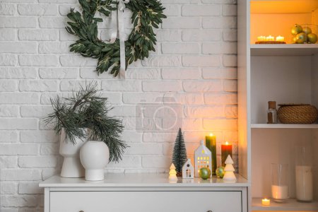 Téléchargez les photos : Vases avec branches de sapin, bougeoirs, sapins de Noël et boules sur la commode dans le salon - en image libre de droit
