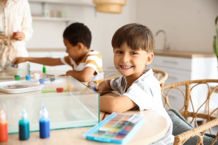 Téléchargez les photos : Petit garçon assis à table dans l'atelier pour la peinture Ebru - en image libre de droit