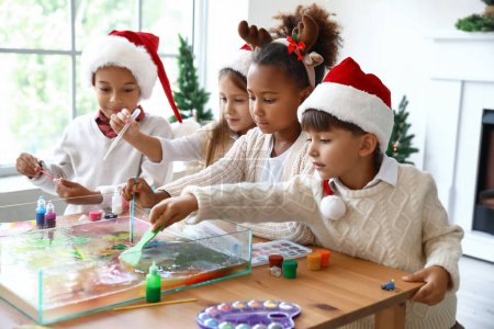 Téléchargez les photos : Petits enfants en chapeaux de Père Noël peignant sur l'eau à l'atelier. Art de l'Èbre - en image libre de droit