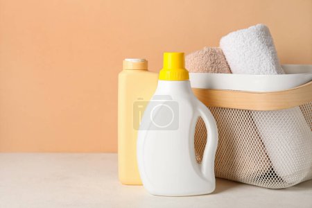 Photo for Laundry detergents with towels on table against beige background - Royalty Free Image