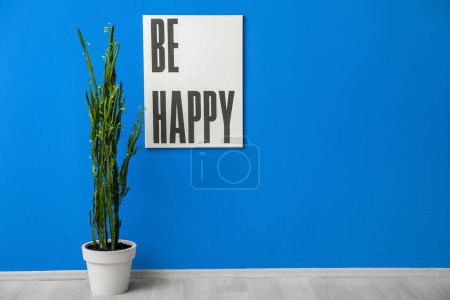 Foto de Cactus verde y cartel cerca de la pared azul en la habitación - Imagen libre de derechos