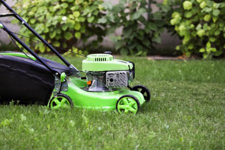 Photo for Modern lawn mower on fresh green grass in garden - Royalty Free Image