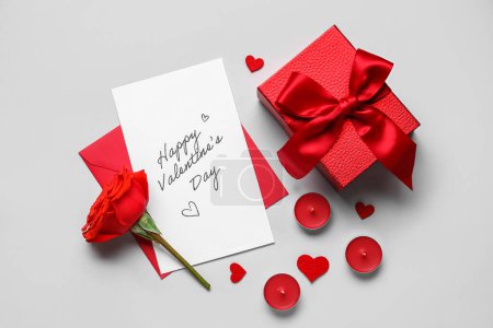 Lettre avec texte FÊTE DE LA SAINE VALENTINE, rose, bougies et cadeau sur fond gris