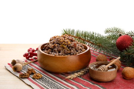 Bowl of Kutya, honey, nuts and Christmas branches on table against white background