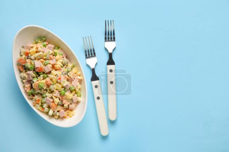 Photo for Bowl of tasty Olivier salad and forks on color background - Royalty Free Image